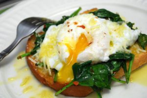 A plate of food with spinach and an egg on it.