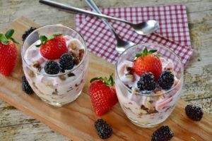 Two glasses of yogurt with strawberries and blackberries.