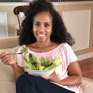A woman sitting on the couch eating salad.