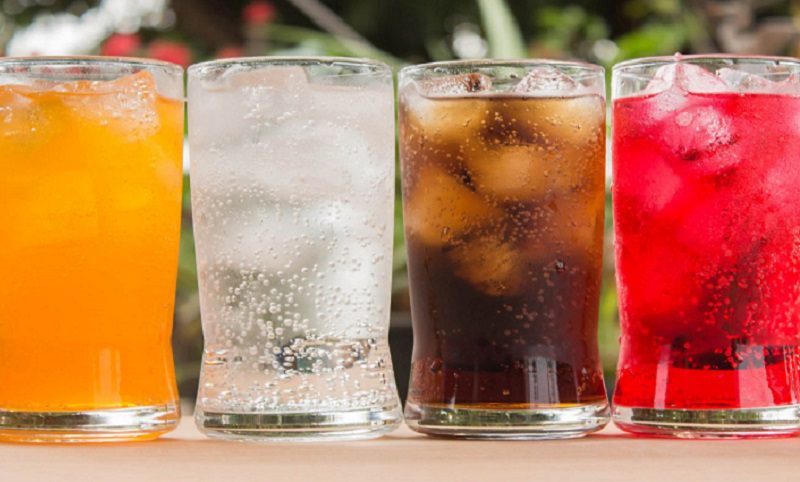 A row of four glasses filled with different drinks.